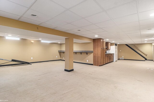 finished basement featuring light carpet, recessed lighting, baseboards, and a paneled ceiling