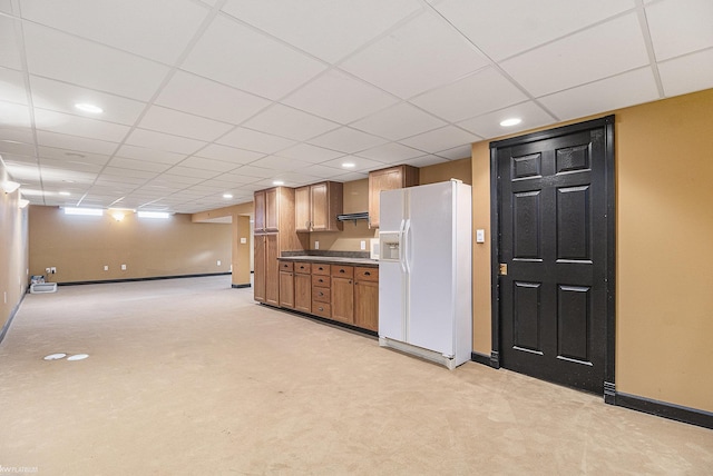 kitchen with white refrigerator with ice dispenser, baseboards, light carpet, dark countertops, and a drop ceiling
