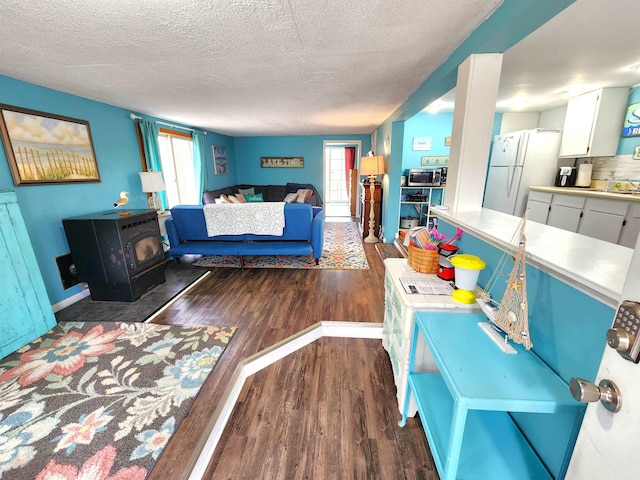 6494 Birch St, Gladwin, MI 48624 - living room with dark wood-style flooring, a textured ceiling, and a wood stove