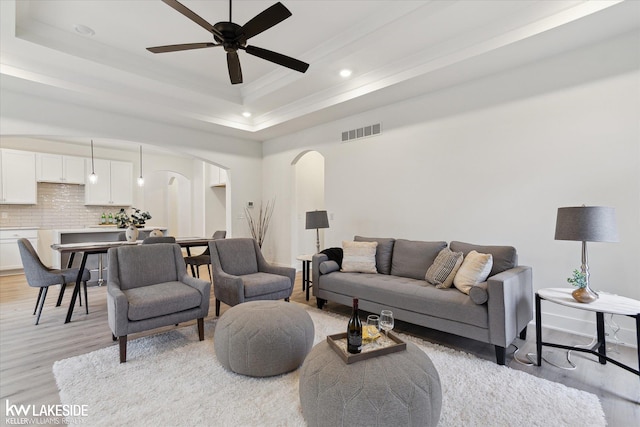 40699 Azalea Ln, Clinton Township, MI 48036 - living room featuring arched walkways, light wood finished floors, a raised ceiling, a ceiling fan, and recessed lighting