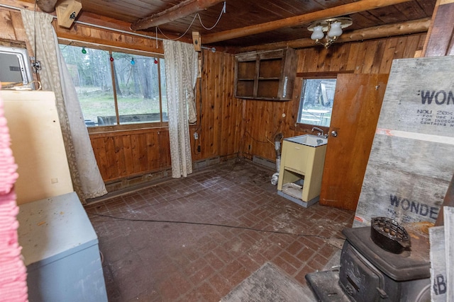 4440 W Cherry Creek Rd, Lewiston, MI 49756 - kitchen featuring brick floors, wooden walls, a wooden ceiling with exposed beams, plenty of natural light, and a wood stove