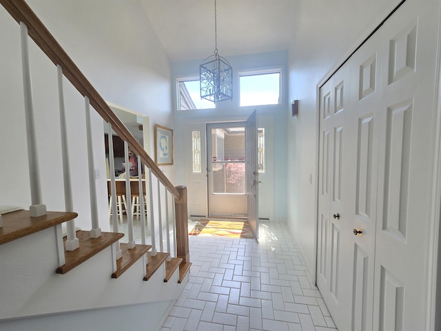 2707 Inverness Dr, Bay City, MI 48706 - foyer entrance featuring stairway, a chandelier, brick flooring, and a towering ceiling