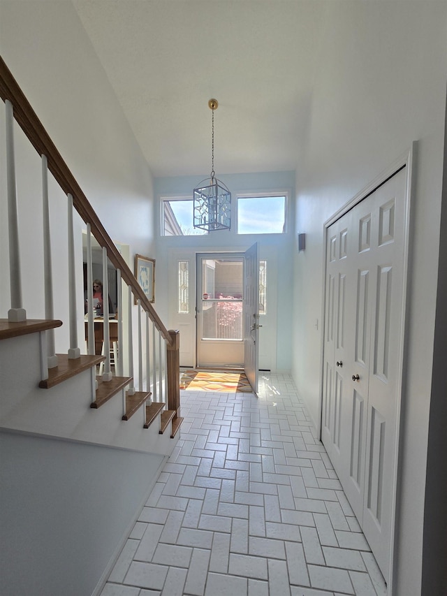 2707 Inverness Dr, Bay City, MI 48706 - foyer with a chandelier, brick floors, stairs, and a high ceiling