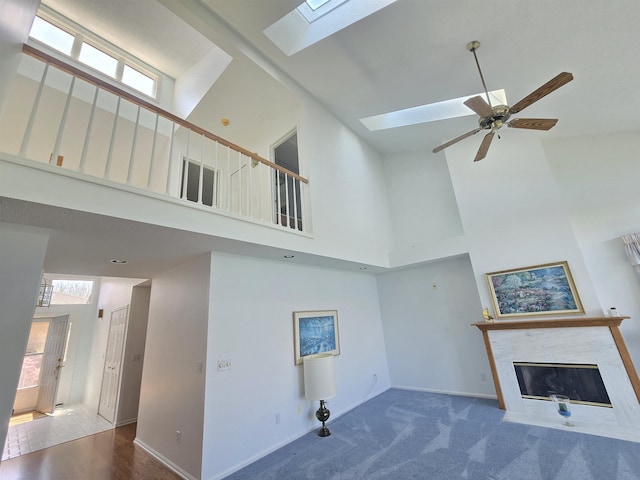 2707 Inverness Dr, Bay City, MI 48706 - unfurnished living room with high vaulted ceiling, a fireplace with flush hearth, a skylight, ceiling fan, and baseboards