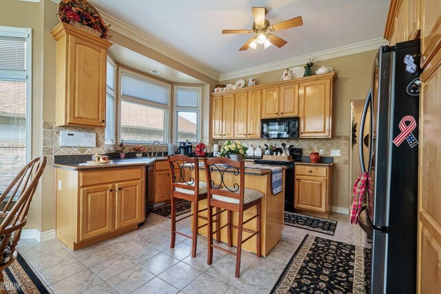 kitchen with black appliances, a sink, ornamental molding, a kitchen bar, and a ceiling fan