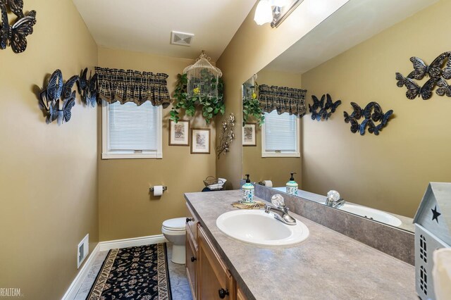 bathroom featuring vanity, toilet, baseboards, and tile patterned floors