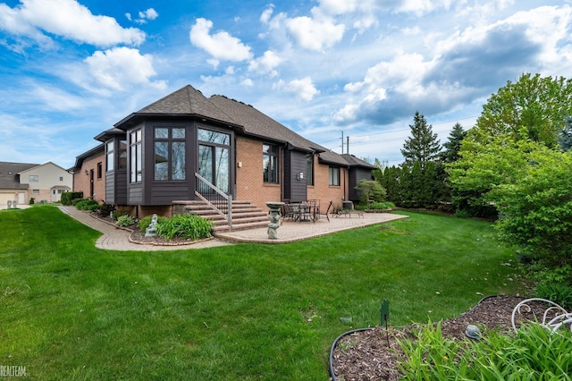 rear view of house featuring a patio, a lawn, entry steps, and brick siding