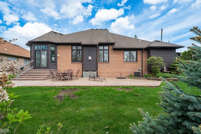 rear view of house with brick siding, a yard, a patio area, and roof with shingles