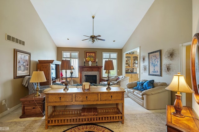 living room with high vaulted ceiling, a ceiling fan, a glass covered fireplace, and baseboards