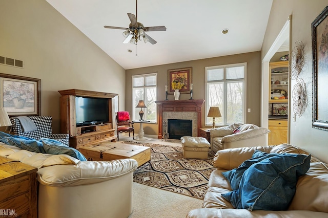 carpeted living room featuring a ceiling fan, high vaulted ceiling, plenty of natural light, and a high end fireplace