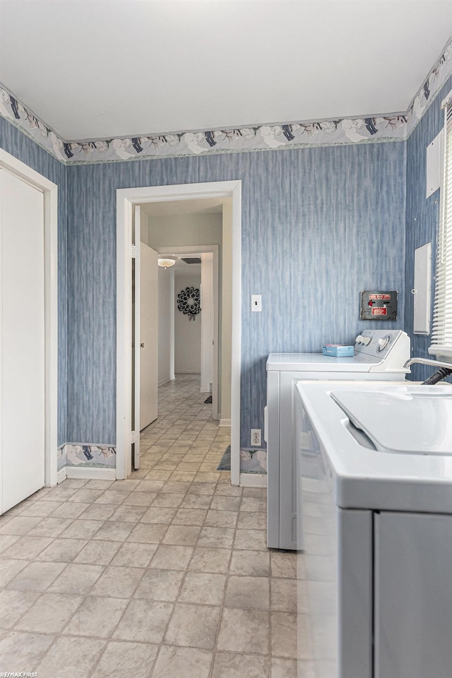 washroom featuring wallpapered walls, washer and dryer, baseboards, and light stone finish floors