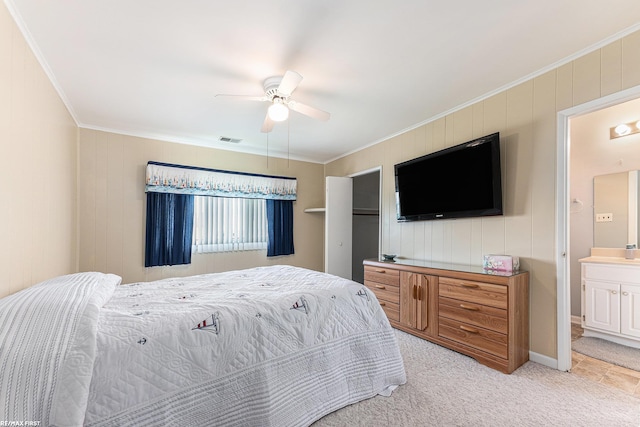bedroom with ornamental molding, light carpet, connected bathroom, ceiling fan, and wooden walls