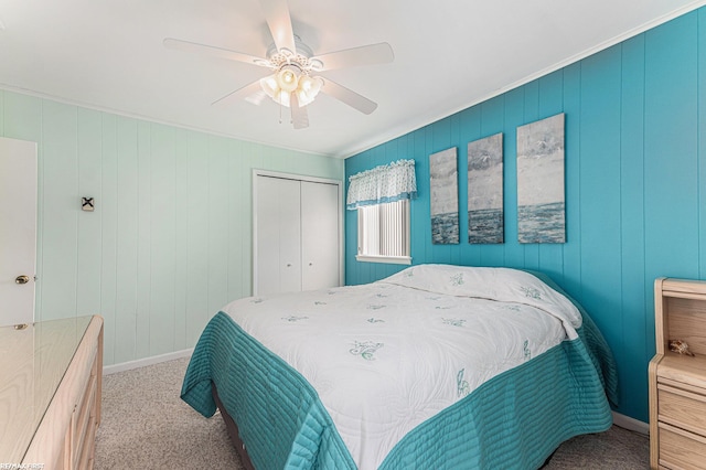 carpeted bedroom with a closet, crown molding, ceiling fan, and baseboards