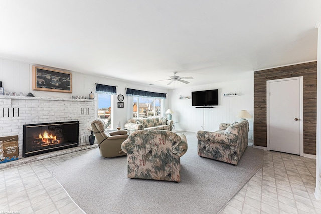 living area with wood walls, a ceiling fan, and a brick fireplace