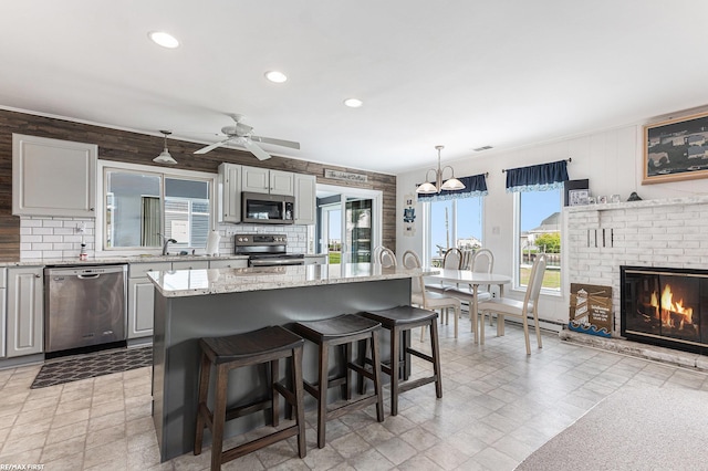 kitchen with appliances with stainless steel finishes, a breakfast bar area, light stone counters, recessed lighting, and ceiling fan