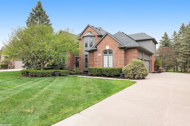 view of front facade with brick siding, a front yard, driveway, and roof with shingles