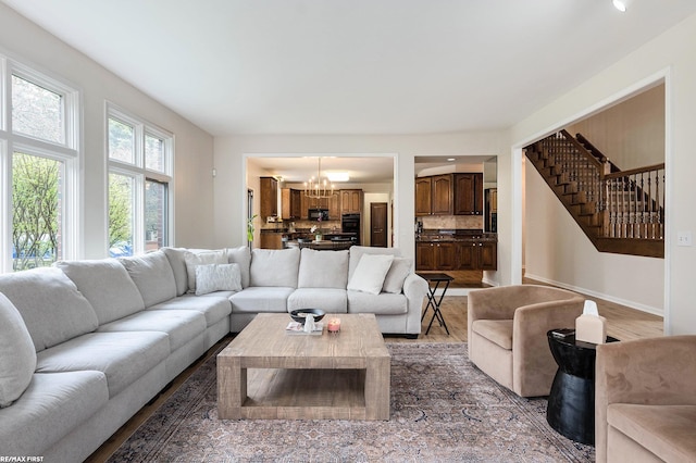 living room featuring a chandelier, stairway, wood finished floors, and baseboards