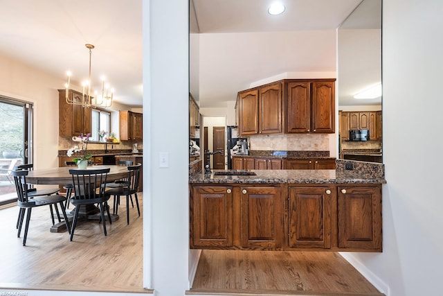kitchen featuring a sink, light wood-style flooring, a chandelier, and decorative backsplash