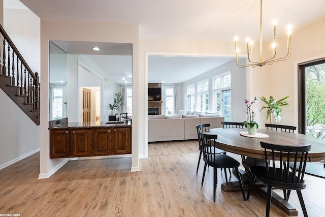 dining room with a chandelier, a fireplace, light wood-type flooring, plenty of natural light, and recessed lighting