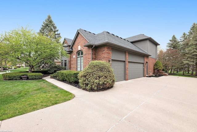 view of front facade featuring brick siding, a garage, driveway, and a front yard