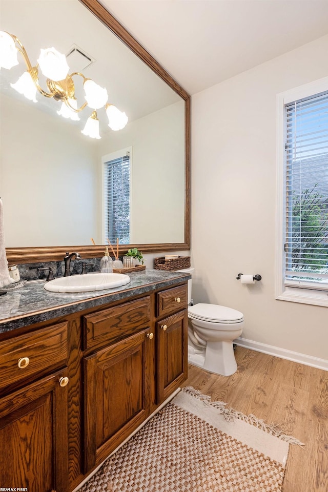 bathroom with a chandelier, wood finished floors, toilet, and vanity