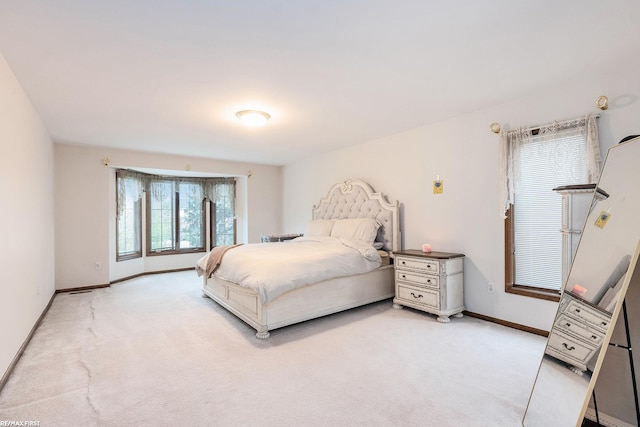 bedroom featuring light colored carpet and baseboards