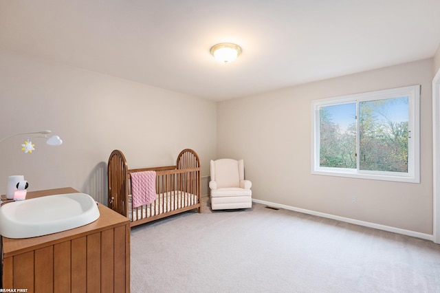 bedroom featuring light colored carpet, a sink, baseboards, and a nursery area