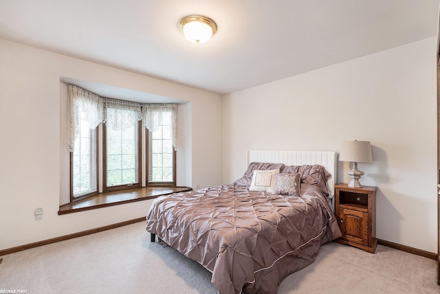 bedroom featuring light carpet and baseboards