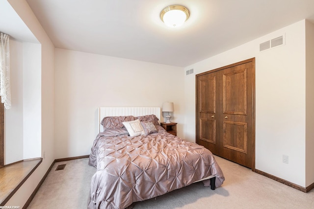 bedroom featuring light colored carpet, baseboards, and a closet