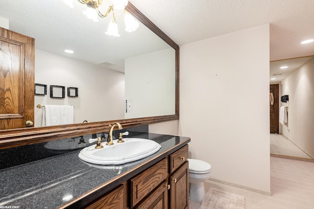 bathroom with toilet, tile patterned floors, vanity, a textured ceiling, and recessed lighting