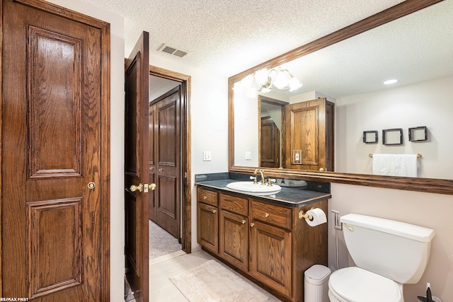 bathroom with a textured ceiling, toilet, vanity, and tile patterned flooring