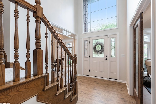 foyer entrance with wood finished floors, stairway, baseboards, and a high ceiling