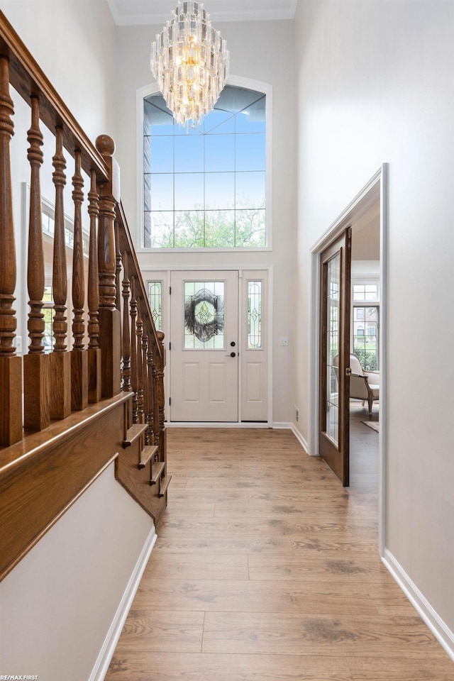 entryway with a chandelier, a high ceiling, light wood-style flooring, plenty of natural light, and stairway