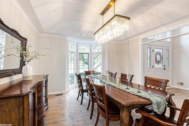 dining area featuring light wood-style floors, ornamental molding, a chandelier, and baseboards