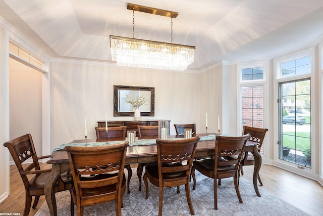 dining area featuring a tray ceiling, a chandelier, wood finished floors, crown molding, and baseboards