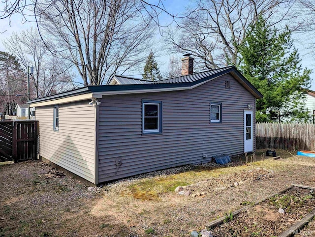 view of home's exterior with a chimney, fence, and metal roof