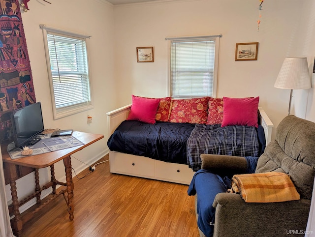 bedroom with wood finished floors, baseboards, and crown molding