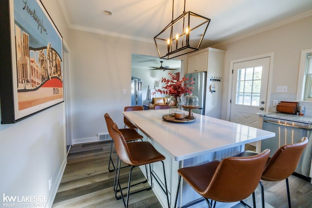 dining space with a ceiling fan, wood finished floors, ornamental molding, a chandelier, and baseboards
