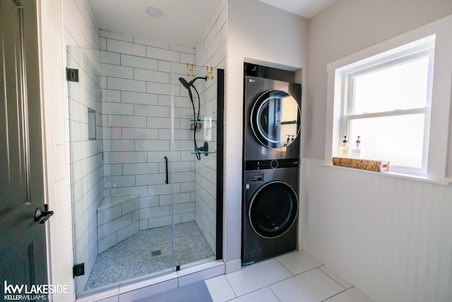 bathroom featuring stacked washer and clothes dryer, tile patterned floors, and a stall shower