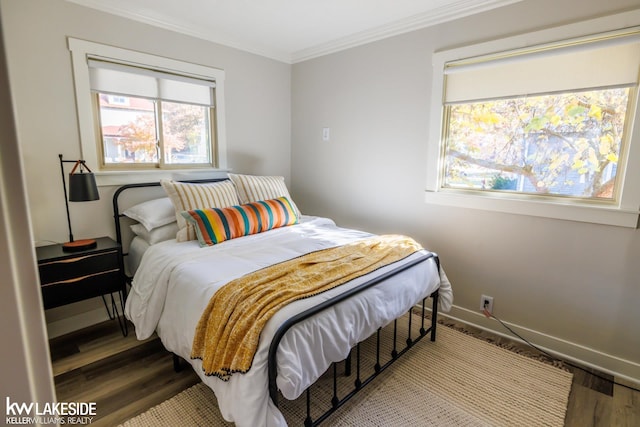 bedroom featuring wood finished floors, ornamental molding, and baseboards