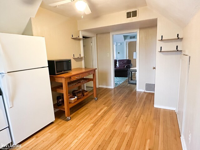 kitchen with freestanding refrigerator, stainless steel microwave, light wood finished floors, a ceiling fan, and baseboards