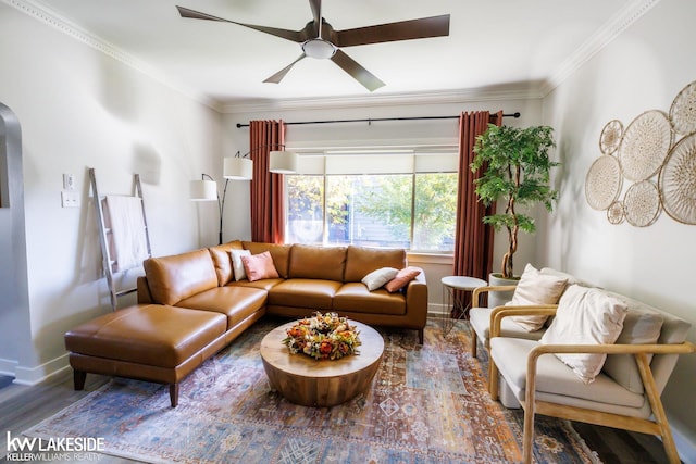 living room featuring wood finished floors, a ceiling fan, baseboards, crown molding, and arched walkways