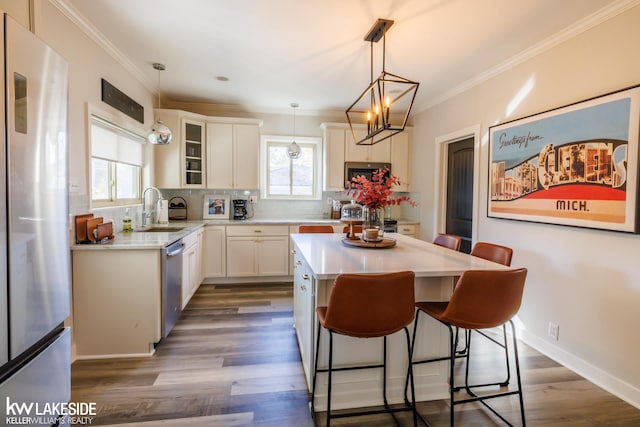 kitchen with stainless steel appliances, a sink, decorative backsplash, light countertops, and a breakfast bar