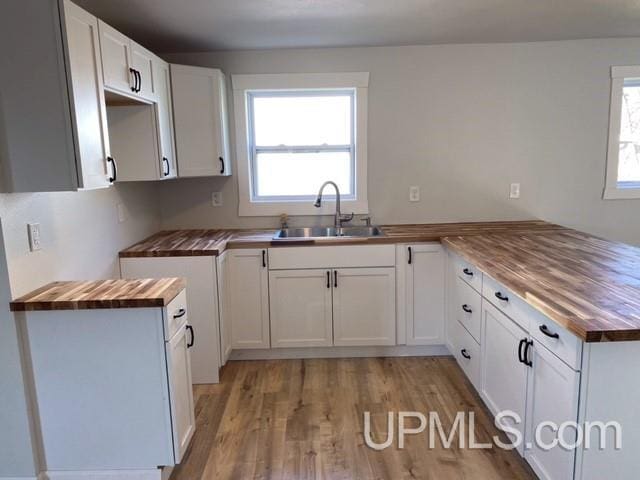 1005 W Brown St, Iron Mountain, MI 49801 - kitchen featuring butcher block countertops, a sink, a peninsula, light wood-style flooring, and white cabinetry