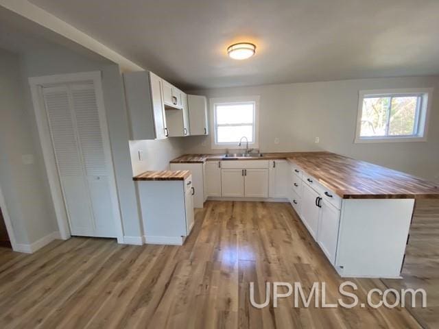 1005 W Brown St, Iron Mountain, MI 49801 - kitchen featuring wooden counters, a peninsula, light wood-style floors, a sink, and white cabinetry