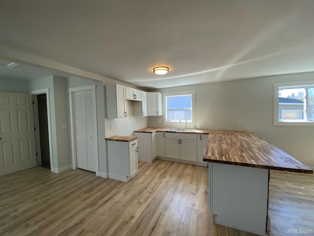 1005 W Brown St, Iron Mountain, MI 49801 - kitchen with wood counters, a peninsula, light wood-style flooring, and white cabinetry