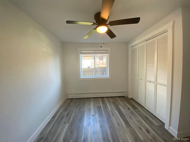 1005 W Brown St, Iron Mountain, MI 49801 - unfurnished bedroom with baseboard heating, wood finished floors, baseboards, a closet, and a ceiling fan