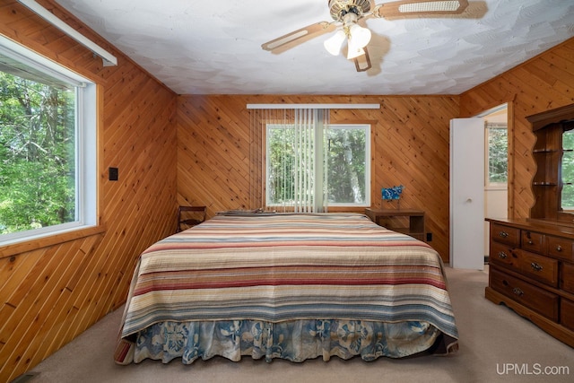 25358 Branch Rd, Michigamme, MI 49861 - carpeted bedroom featuring multiple windows, wooden walls, and a ceiling fan