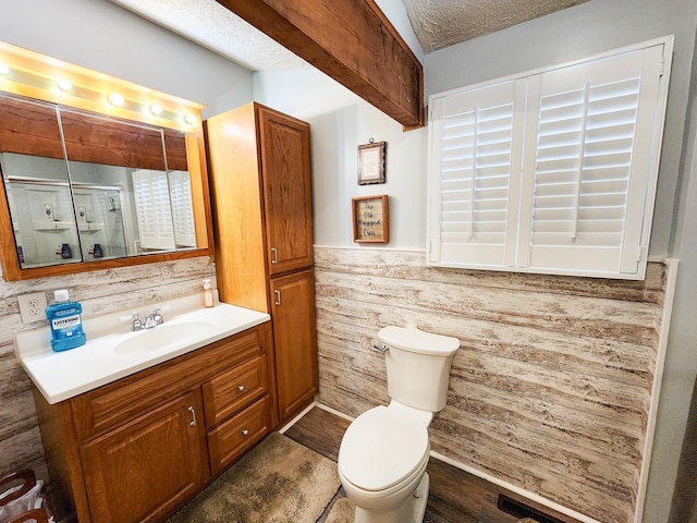 bathroom featuring a stall shower, a wainscoted wall, wood finished floors, vanity, and toilet