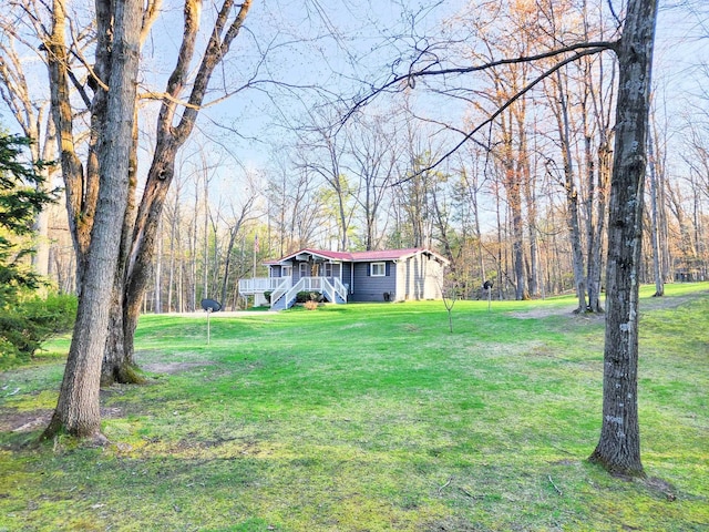 view of grassy yard with stairway and a forest view